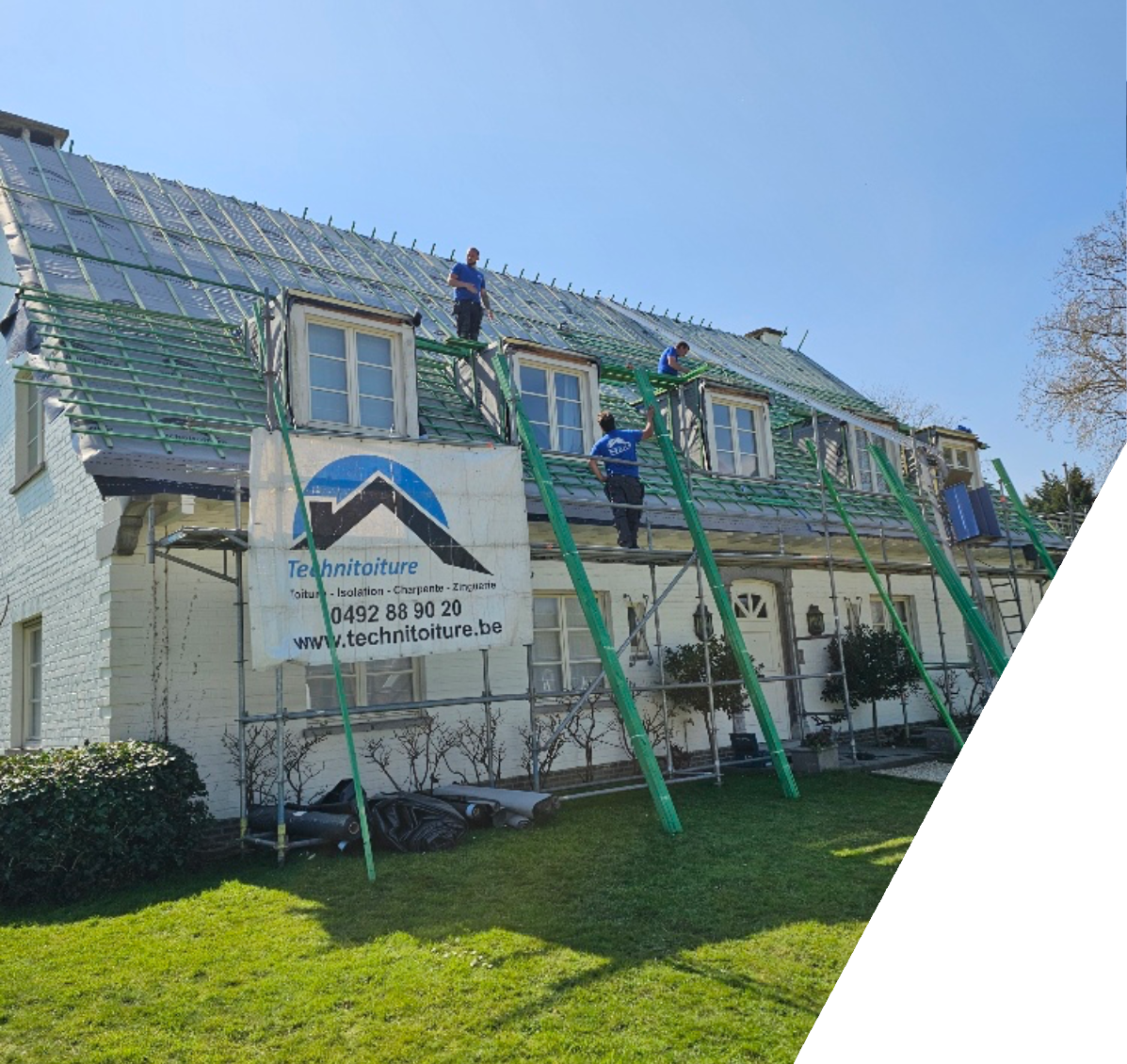 Des ouvriers travaillent sur la charpente d’une toiture inclinée entourée d’échafaudages.