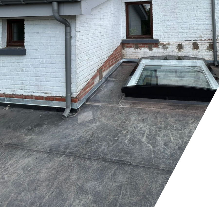 Un toit plat recouvert d’une membrane grise entoure une fenêtre vitrée au pied de murs blancs.